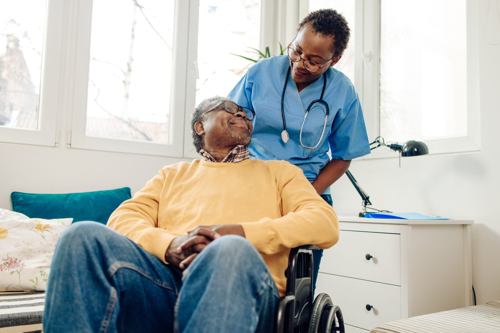 African American senior man in a wheelchair having support from his home caregiver.