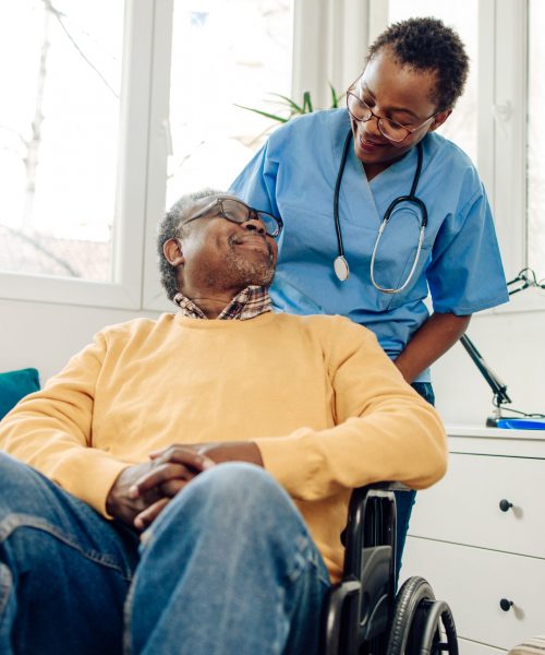 African American senior man in a wheelchair having support from his home caregiver.